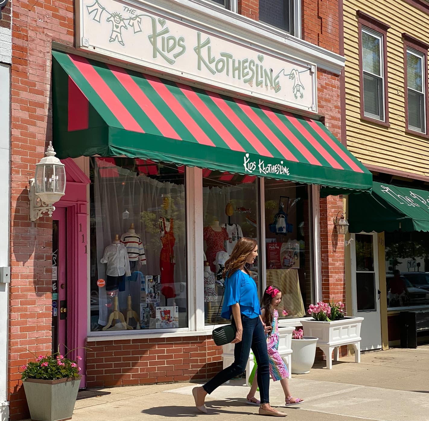 A woman walking with her daughter in front of a downtown shop